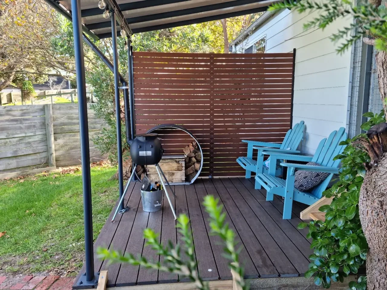 Far View covered deck with BBQ, firewood and blue Adirondack chairs