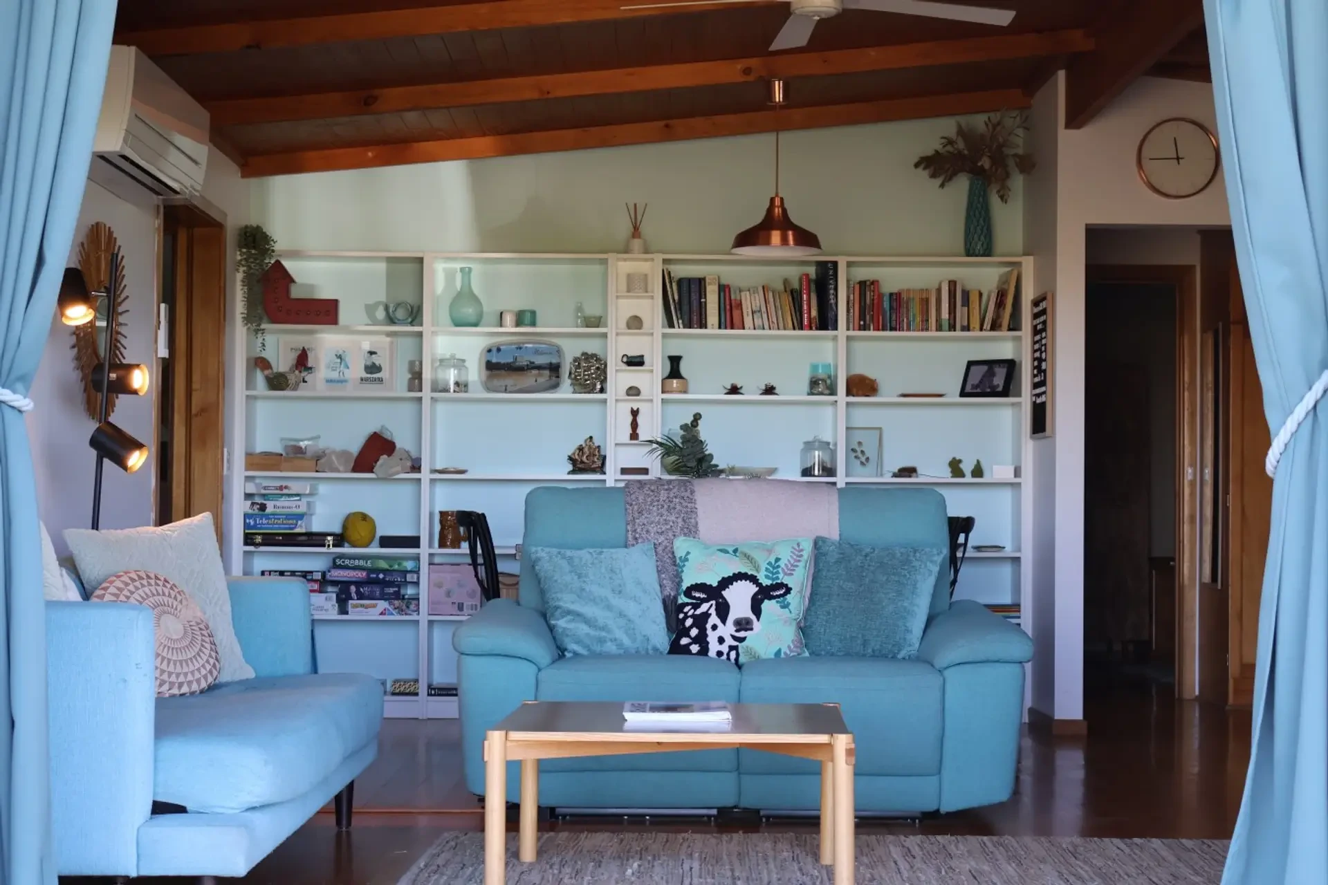Far View lounge room with turquoise sofas, timber beams and bookshelves