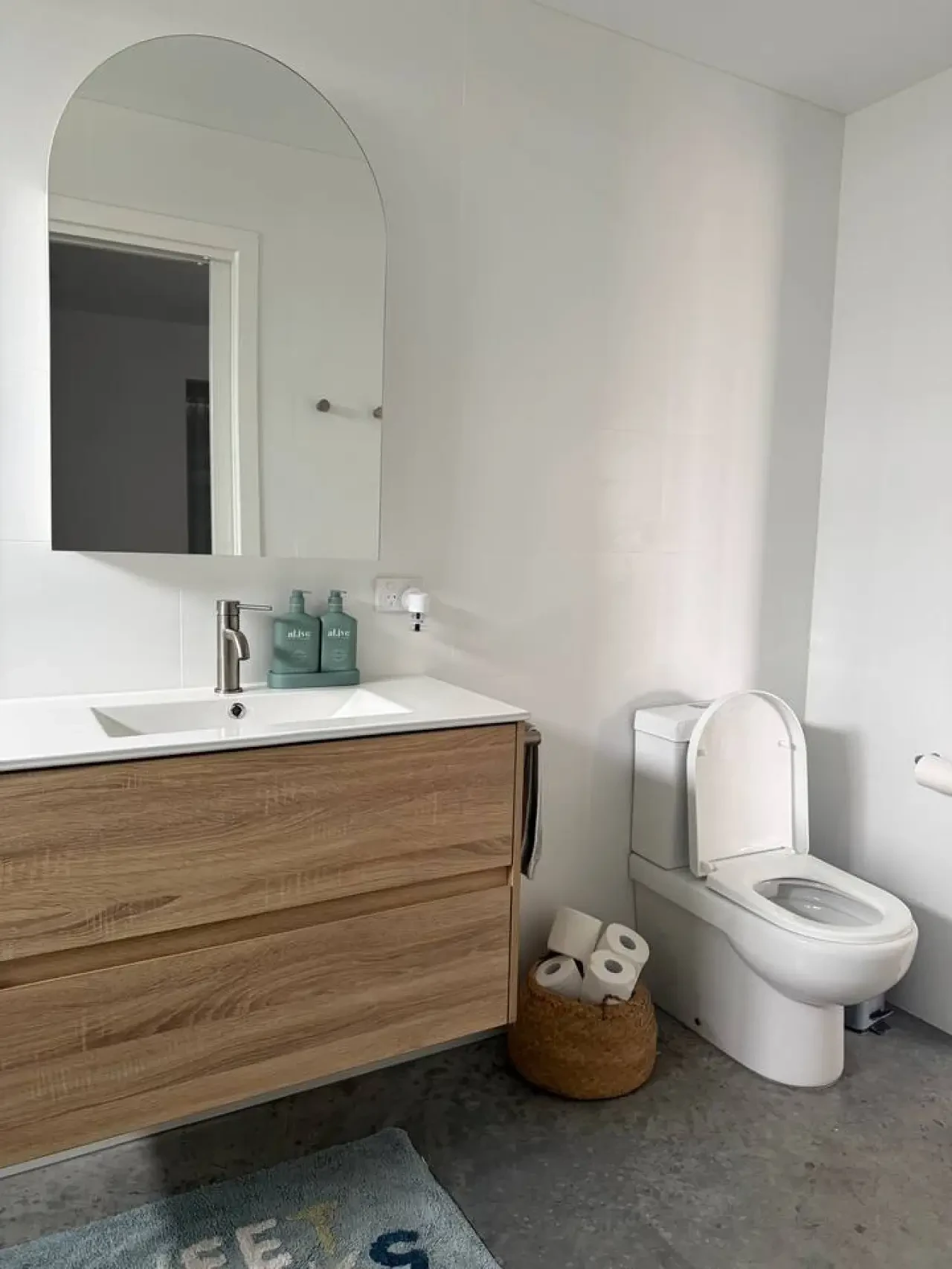 Lancaster Lodge bathroom with timber vanity, arched mirror and concrete floor