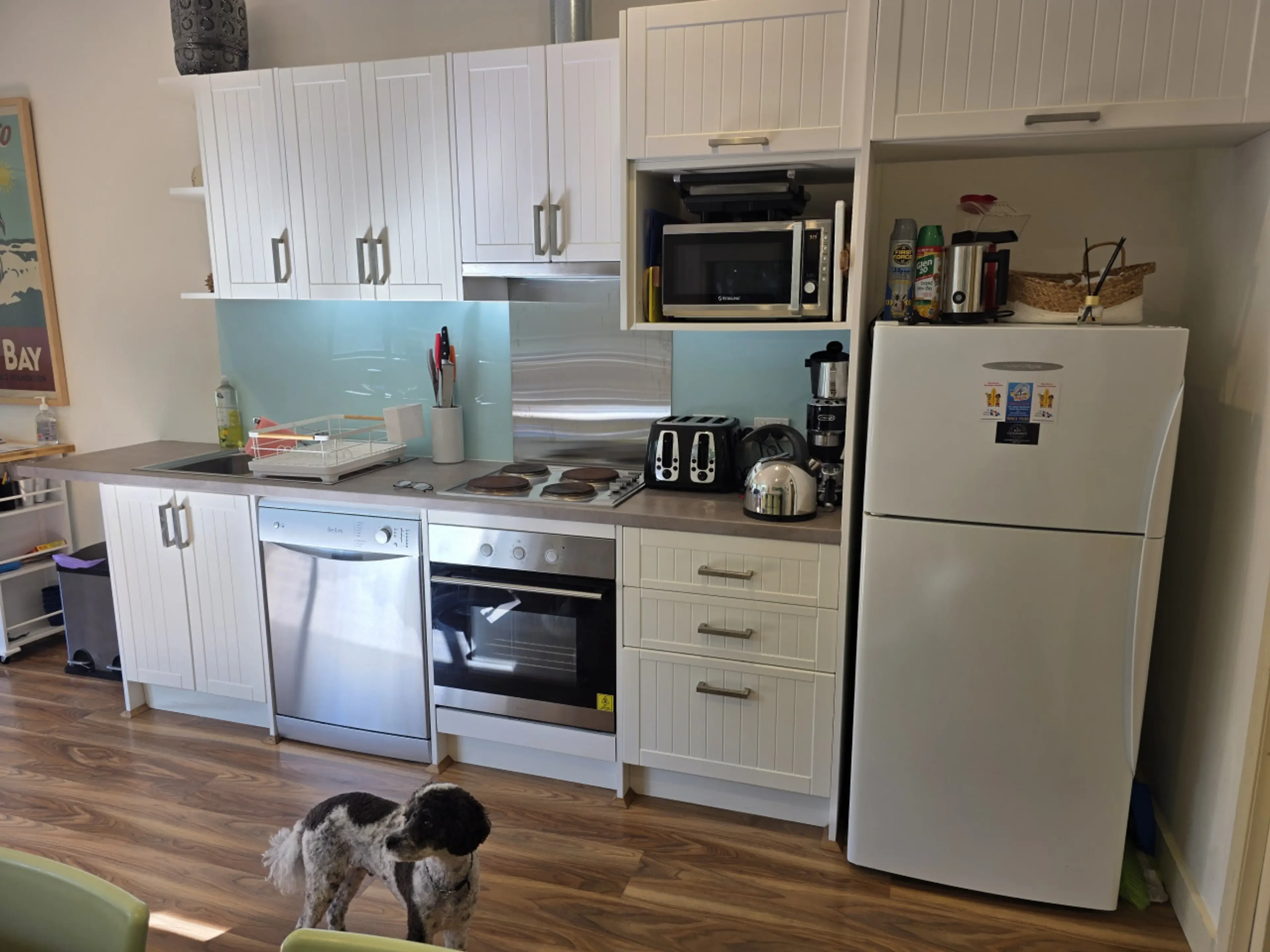 Kitchen with white cabinetry and aqua splashback
