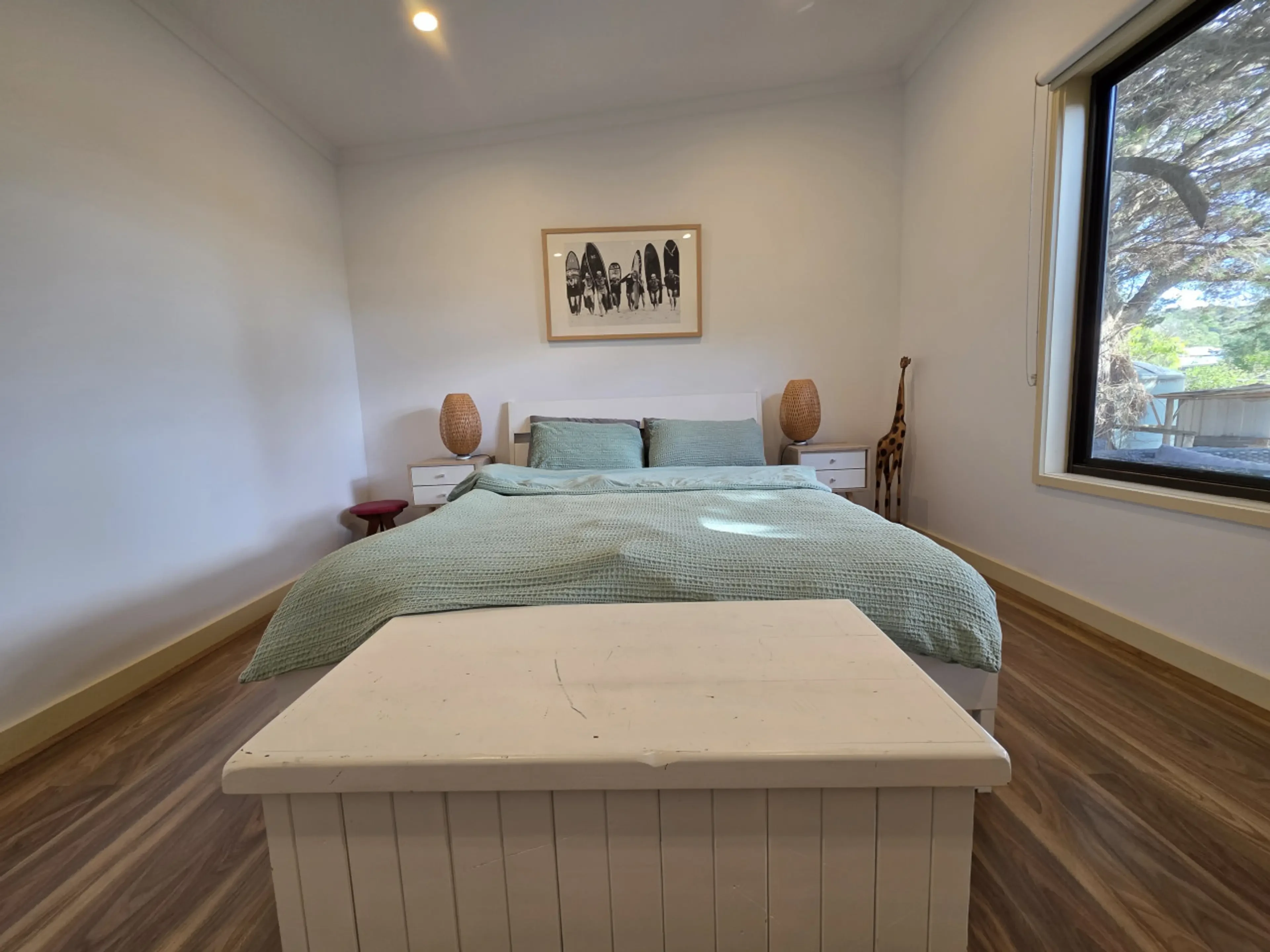 Master bedroom with green bedding and surfboard artwork