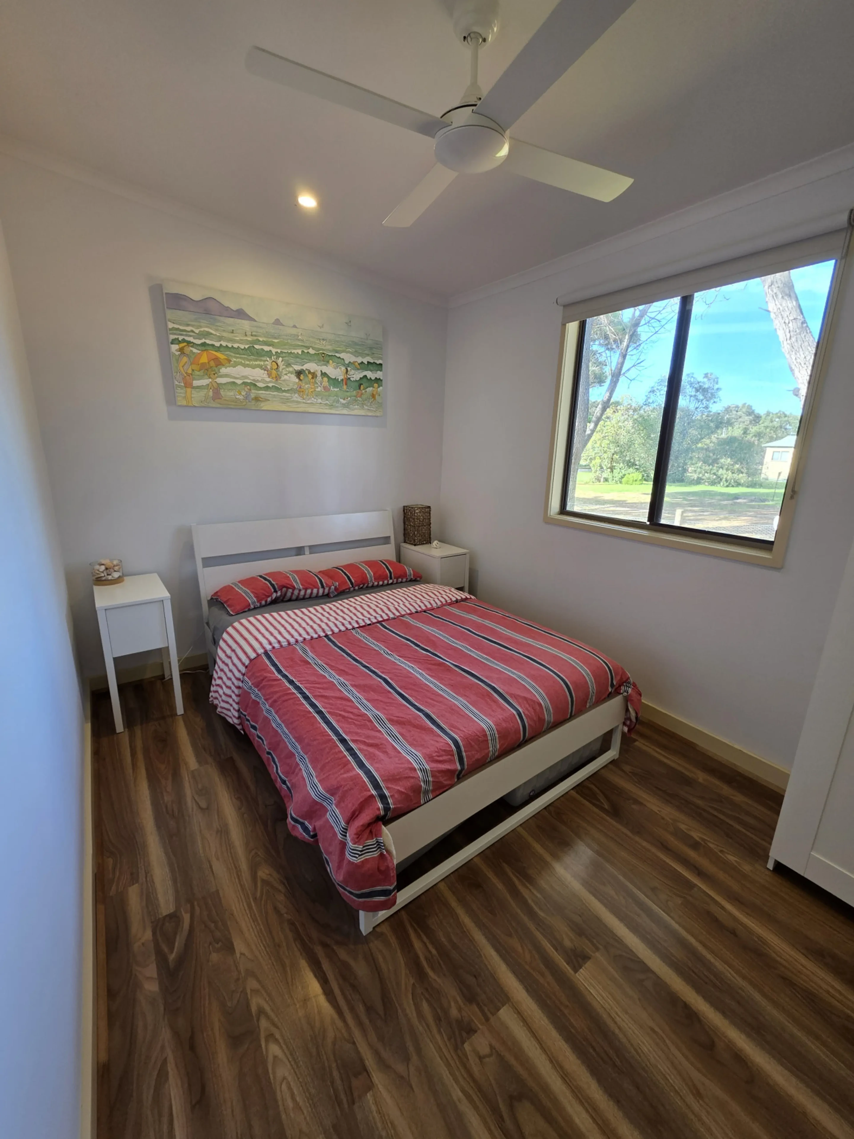 Second bedroom with red striped bedding and beach artwork