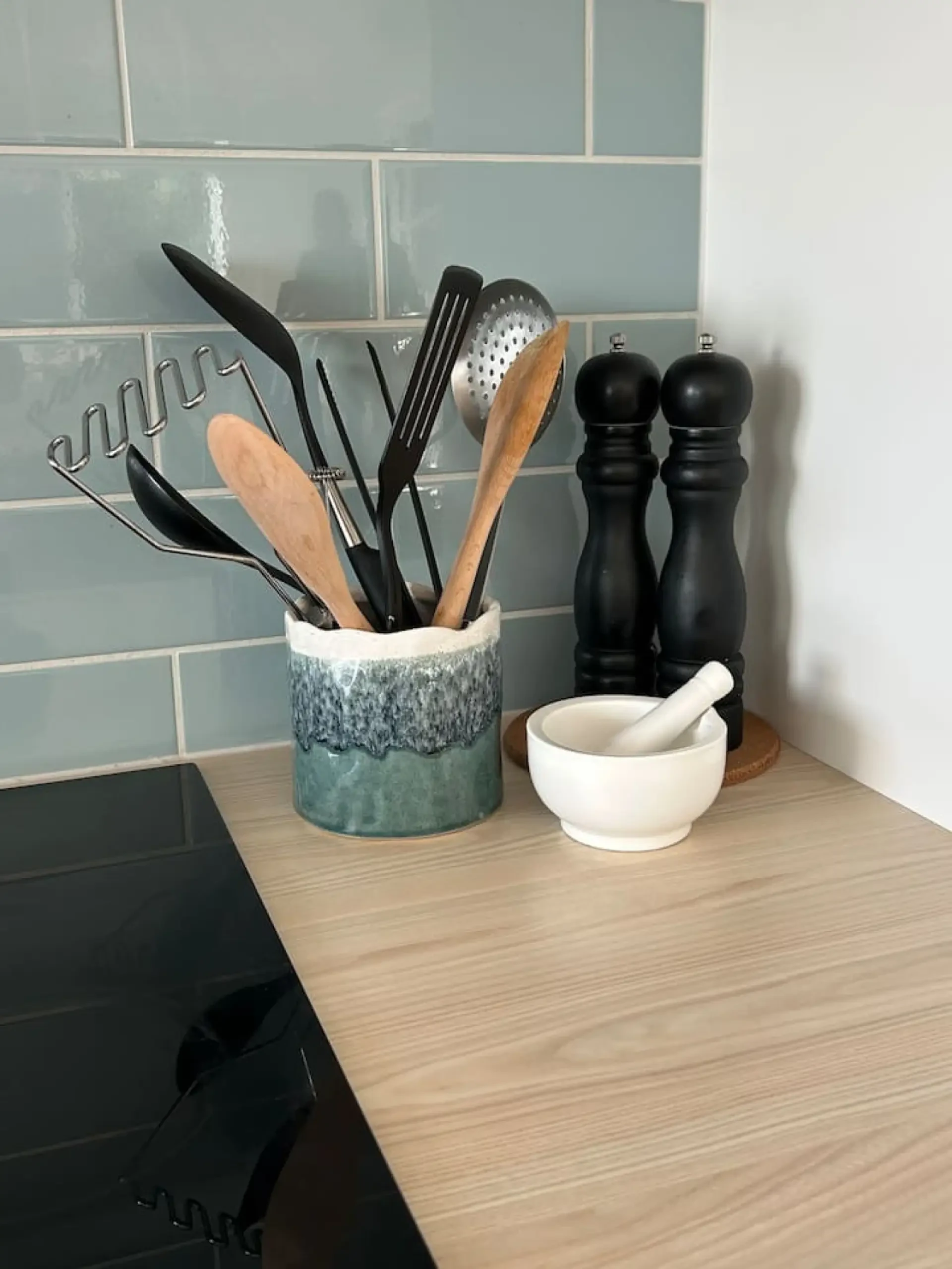 Roo Views kitchen counter with utensils and teal tile backsplash
