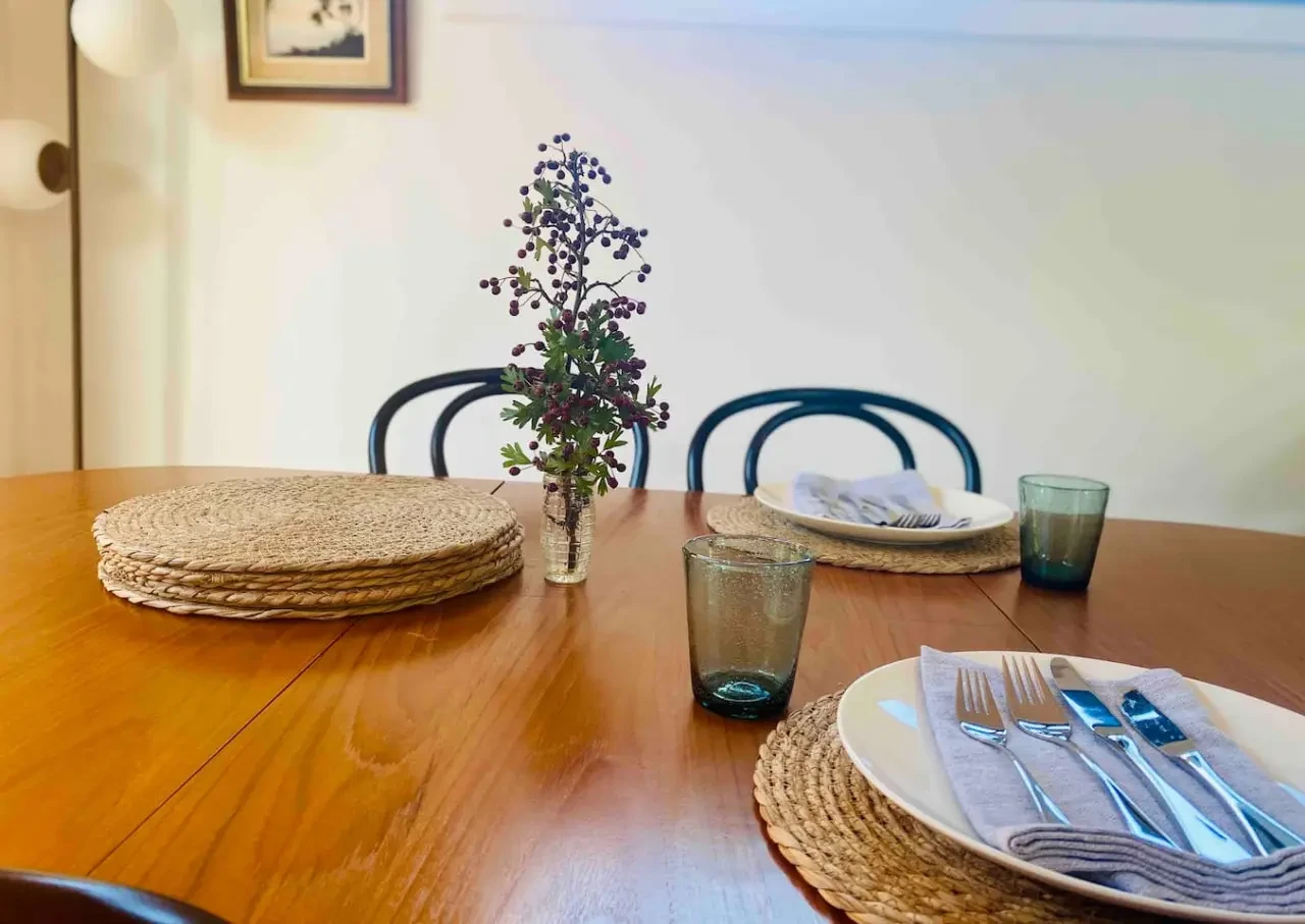 Styled dining table with woven placemats and blue-green glassware